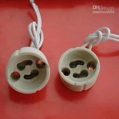 Pair of white GU10 ceramics lampbases with attached wires on red background