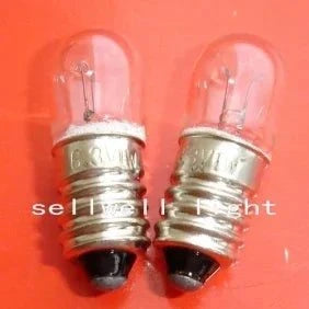 Close-up of two miniature 6.3v 1w E10 base light bulbs with clear glass and metal screw bases on a red background