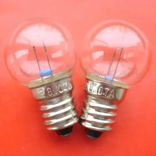 Close-up of two miniature 24V 3W E10 base light bulbs on orange background