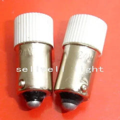 Two 24v LED lights with ba9s base and white ribbed tops on orange background