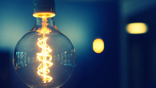 Close-up of a glowing miniature bulb with decorative filament against a blurred background