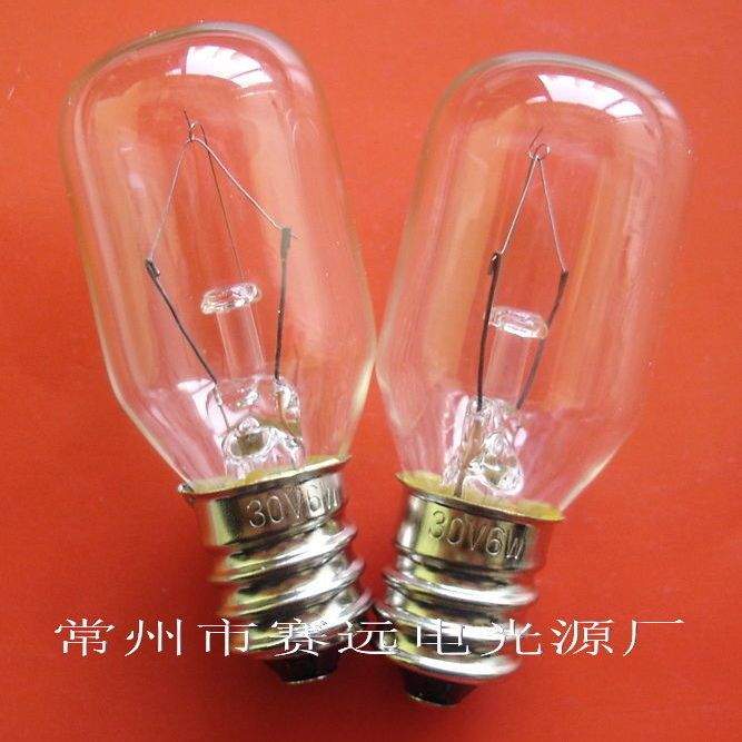 Close-up of two clear E12 screw base instrument bulbs rated 30V 60mA on orange background