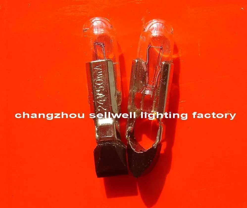 Close-up of two 24V 50MA T5.5KX22 telephone bulbs with metal bases on an orange background